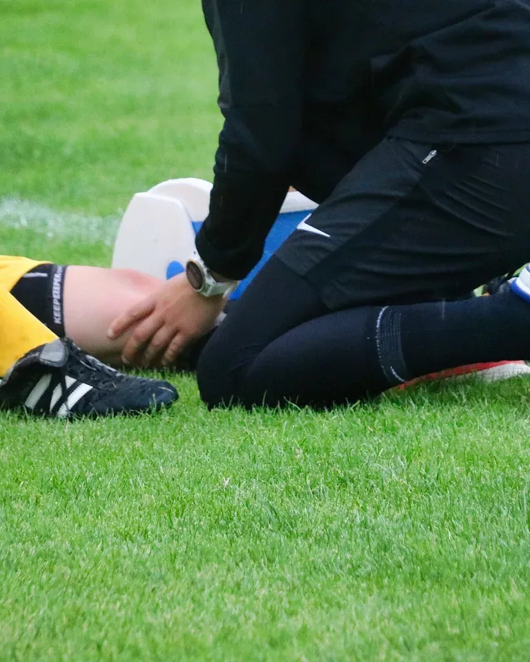 Professionnel de santé soignant un sportif en bord de terrain