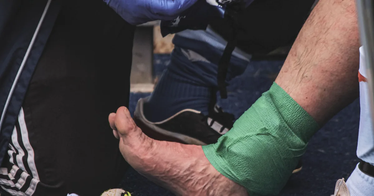 Strapping de cheville posé à un sportif au bord du terrain