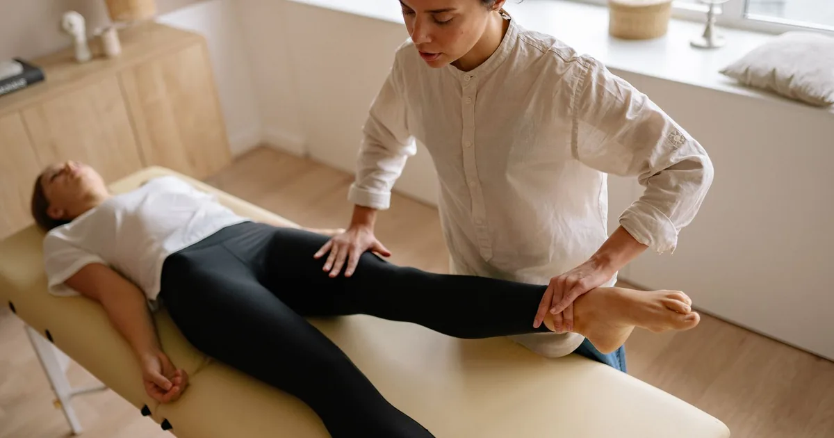 Kinésithérapeute mobilisant la jambe d'une patiente sur une table de soin